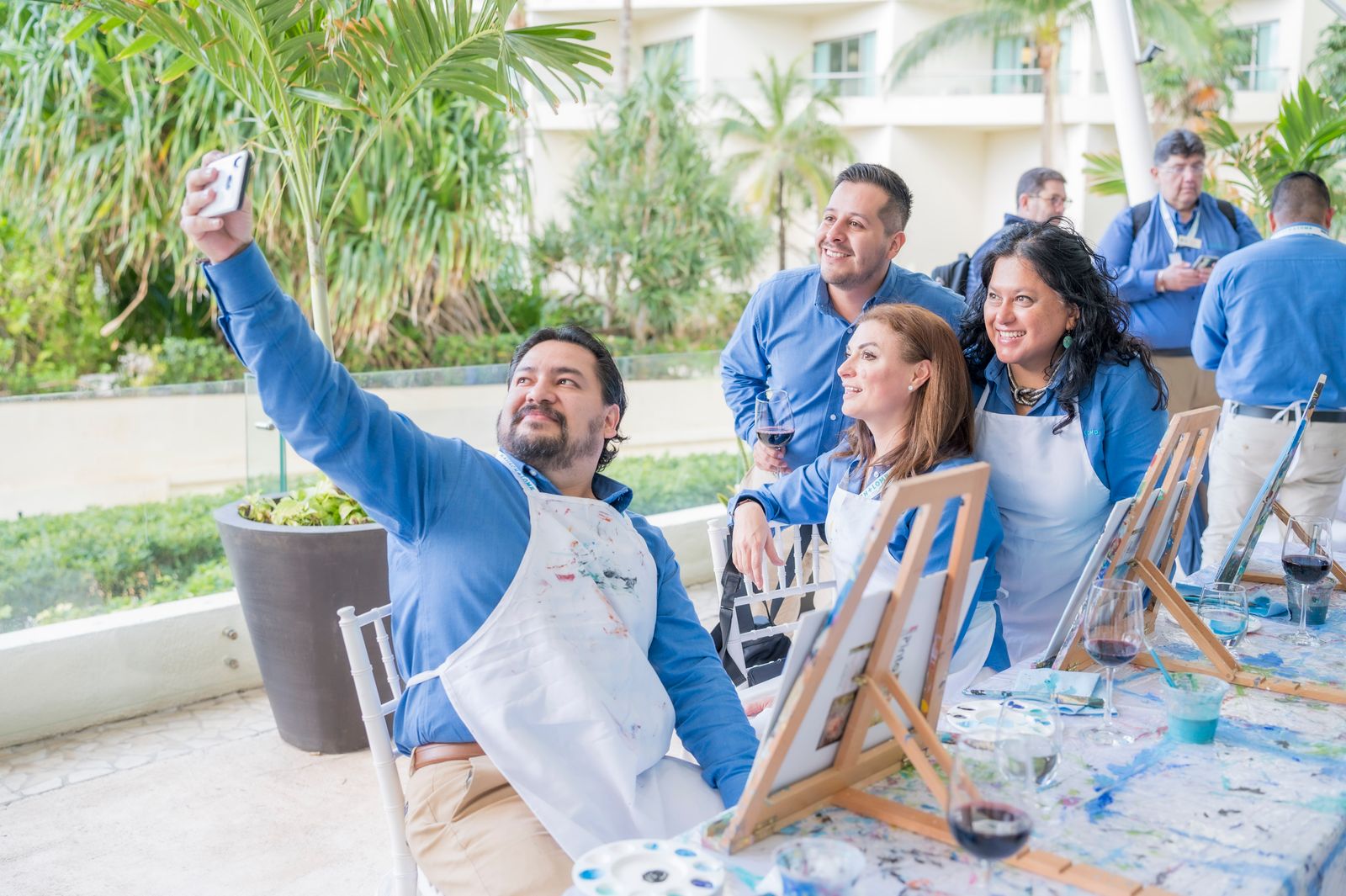 Stock photo of adults taking a selfie beside easels at an outdoor painting workshop.